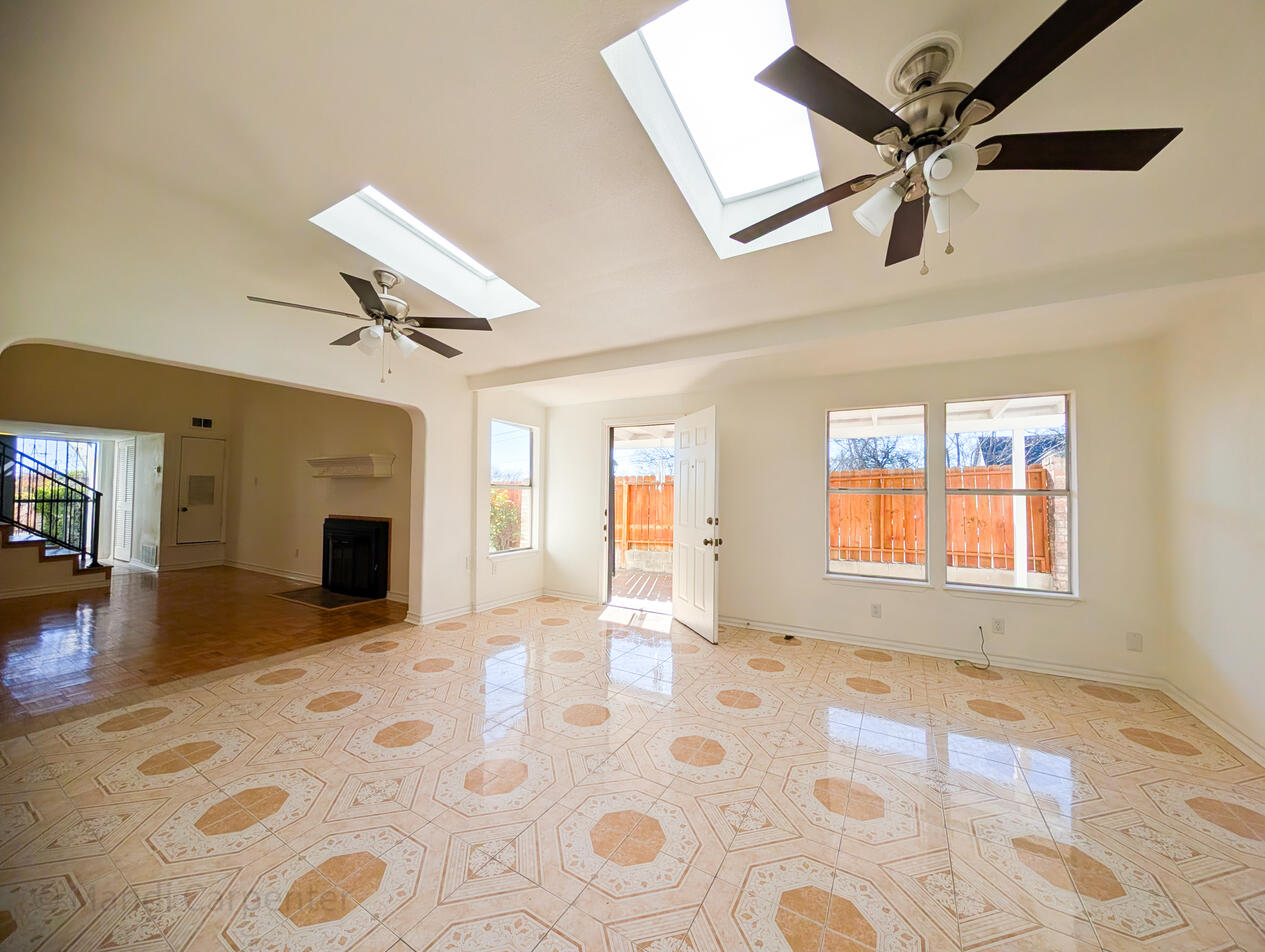 Second living area is well lit with two large skylights, and two room fan lights, along with windows that show the small garden/yard area. The floor is tiled with a decorative pattern