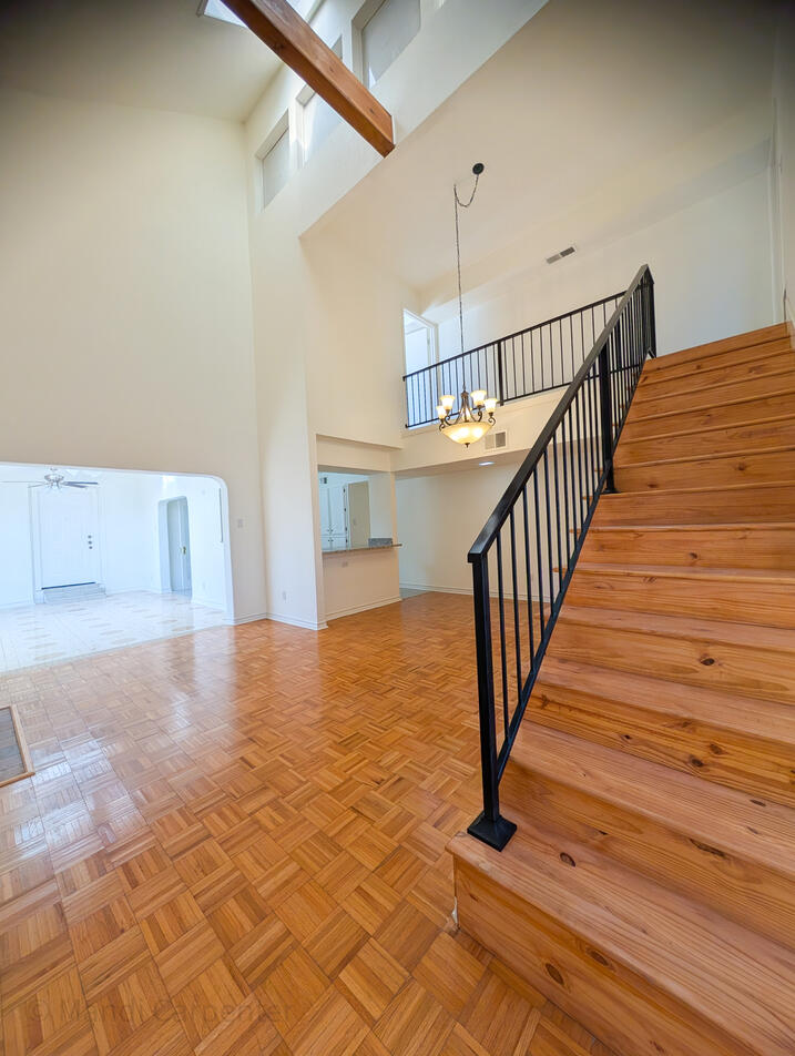 Golden Oak staircase can be seen leading to the second story, Warm and hardy natural wood floors invite you in. Past that you can see the Solid Granite counters of the bar leading to the kitchen